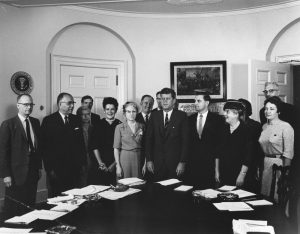 President John F. Kennedy with Members of the Consumer Advisory Council, 1962. Dr Persia Campbell stands beside President Kennedy. Photograph by Abbie Rowe. White House Photographs. John F. Kennedy Presidential Library and Museum, Boston.