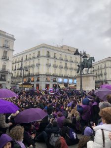 Group of people dressed in purple gathered in a town square
